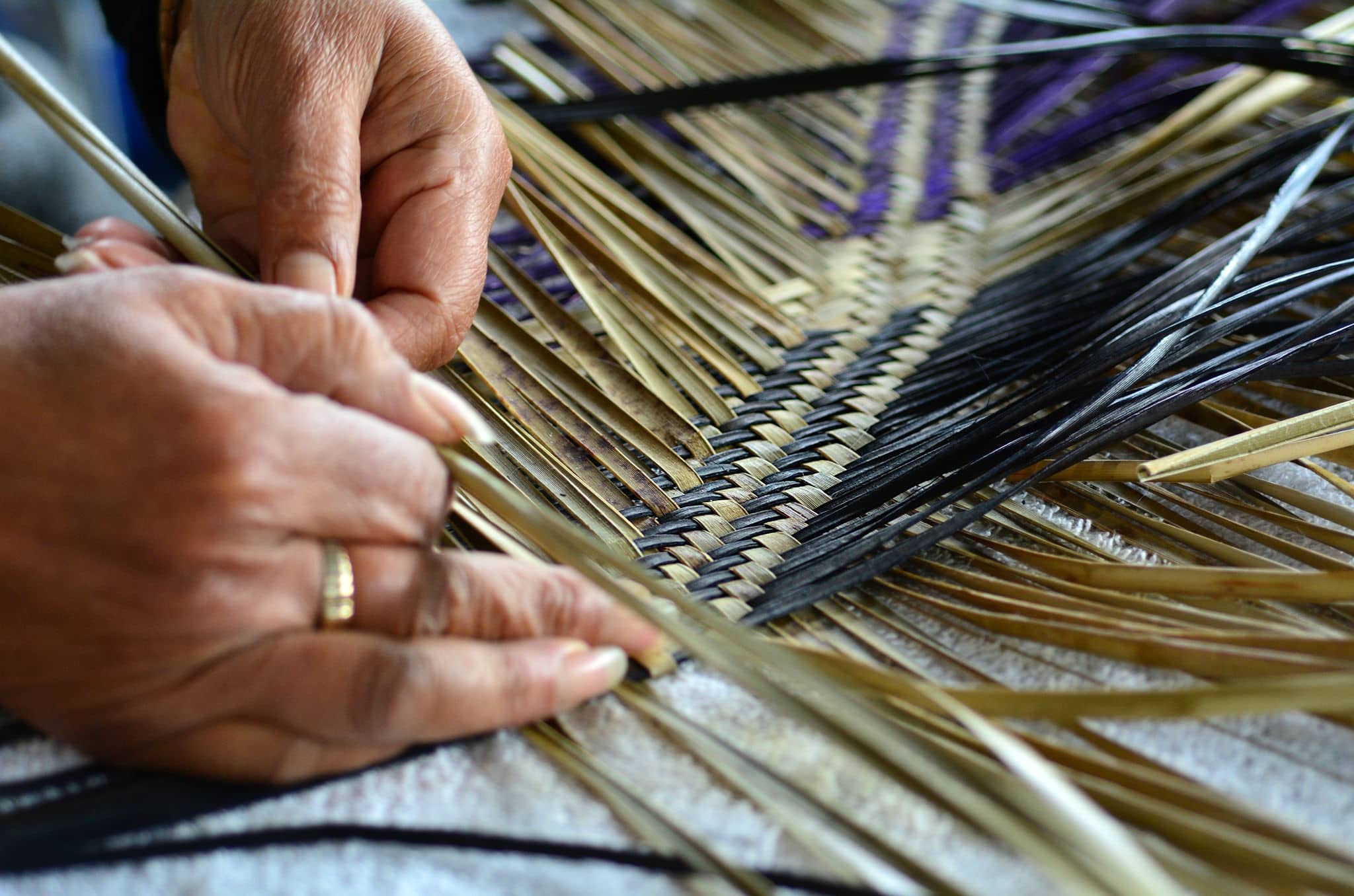 Hands of an old Polynesian Maori woman weaving a traditional woven artwork mat in Auckland, New Zealand.