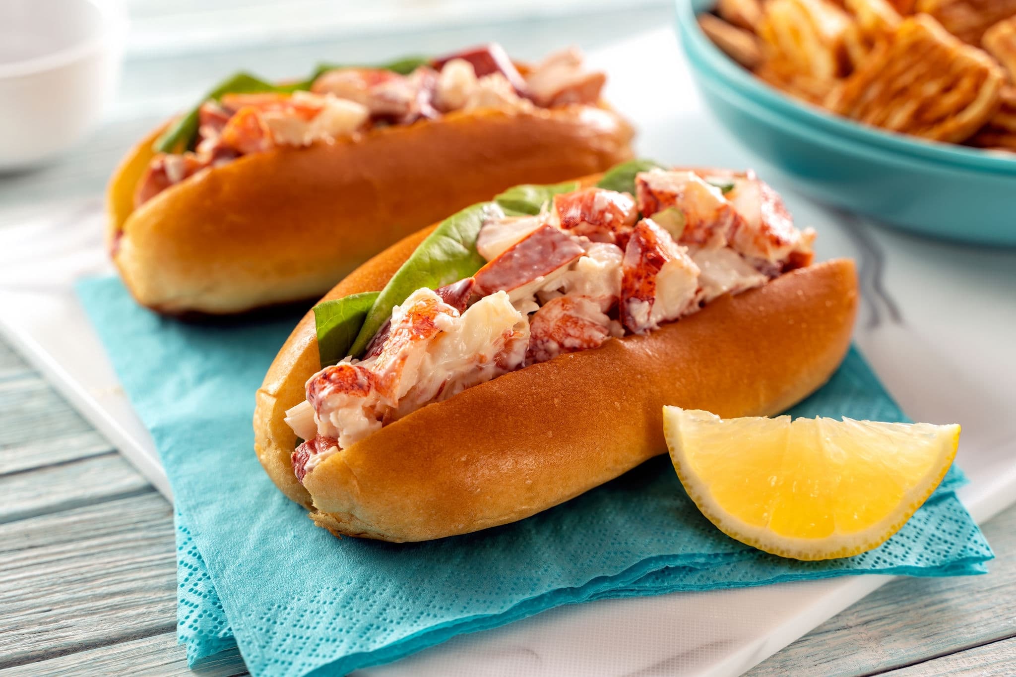 Delicious fresh lobster rolls with lettuce, mayonnaise, and celery on a brioche bun.