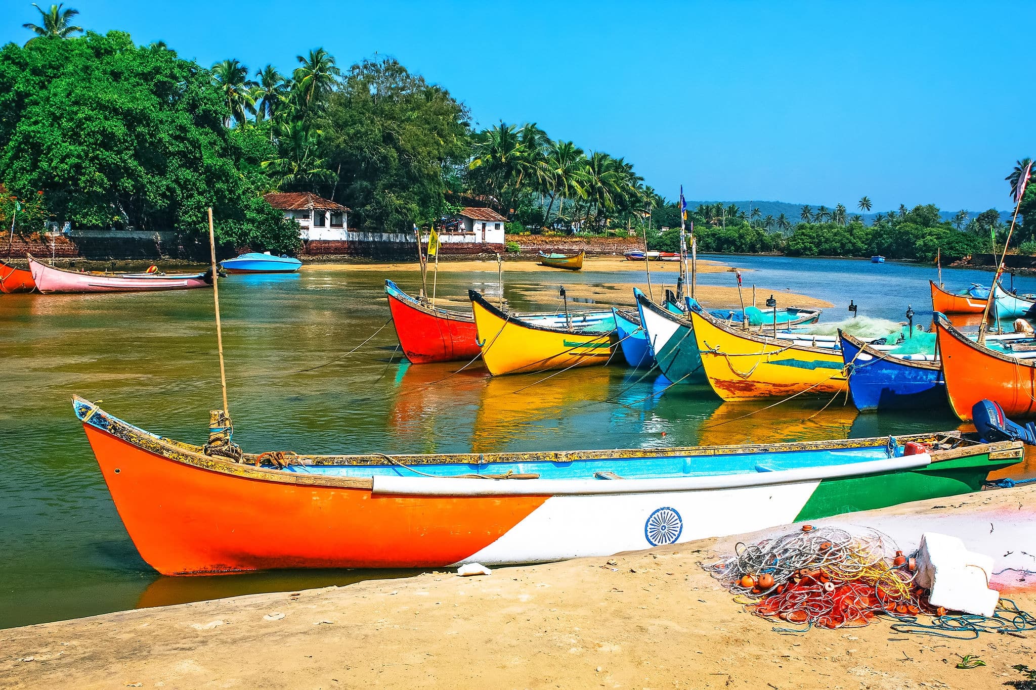 fishing boats on the beach  in tropical with palms, huts and blue sky. Goa, India