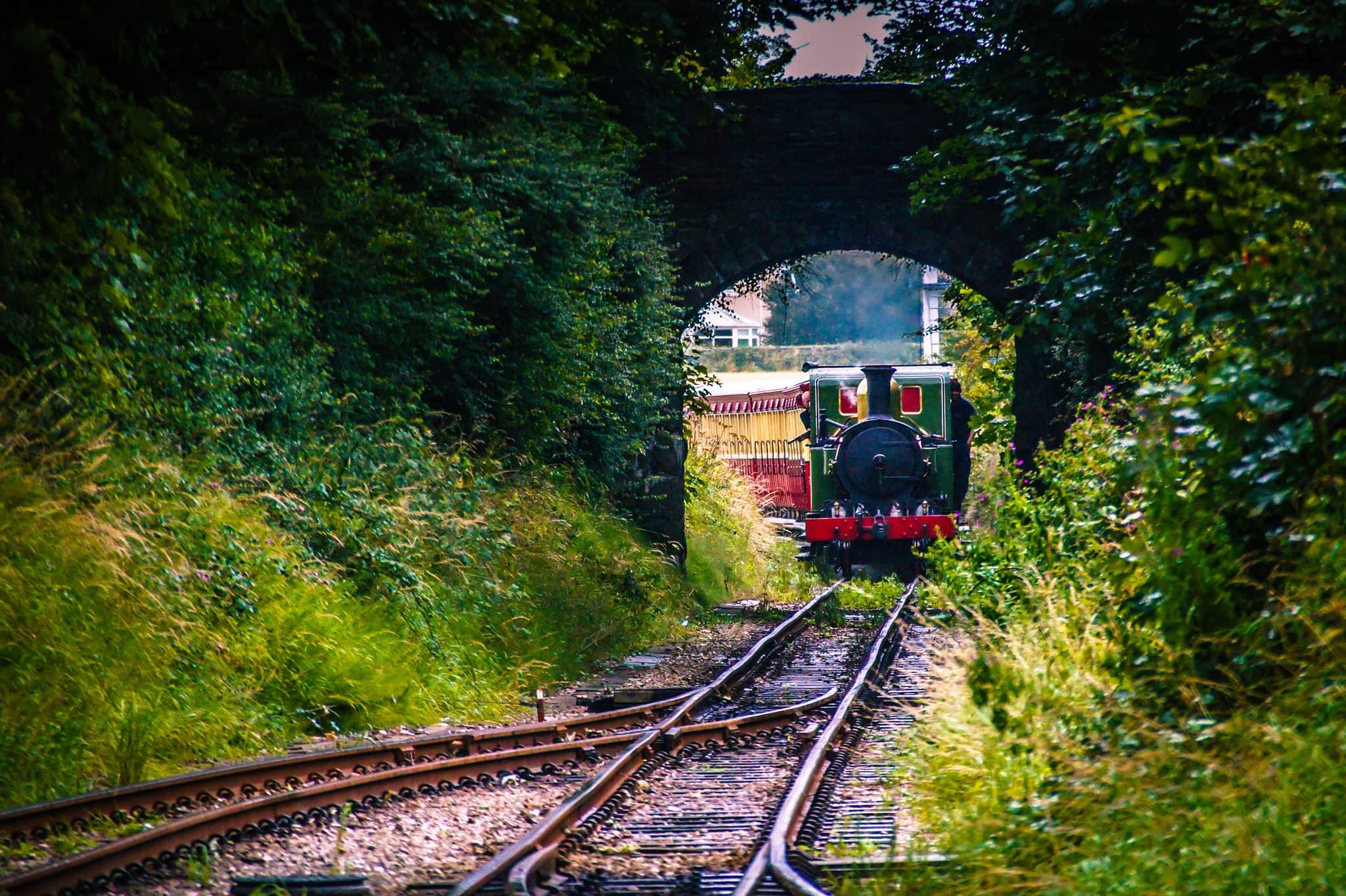 Steam train arriving at the railway train station. Arrival of the train. Steam trains arrive at station. Steam train under the stone bridge. Retro intercity Long distance trains Isle of Man