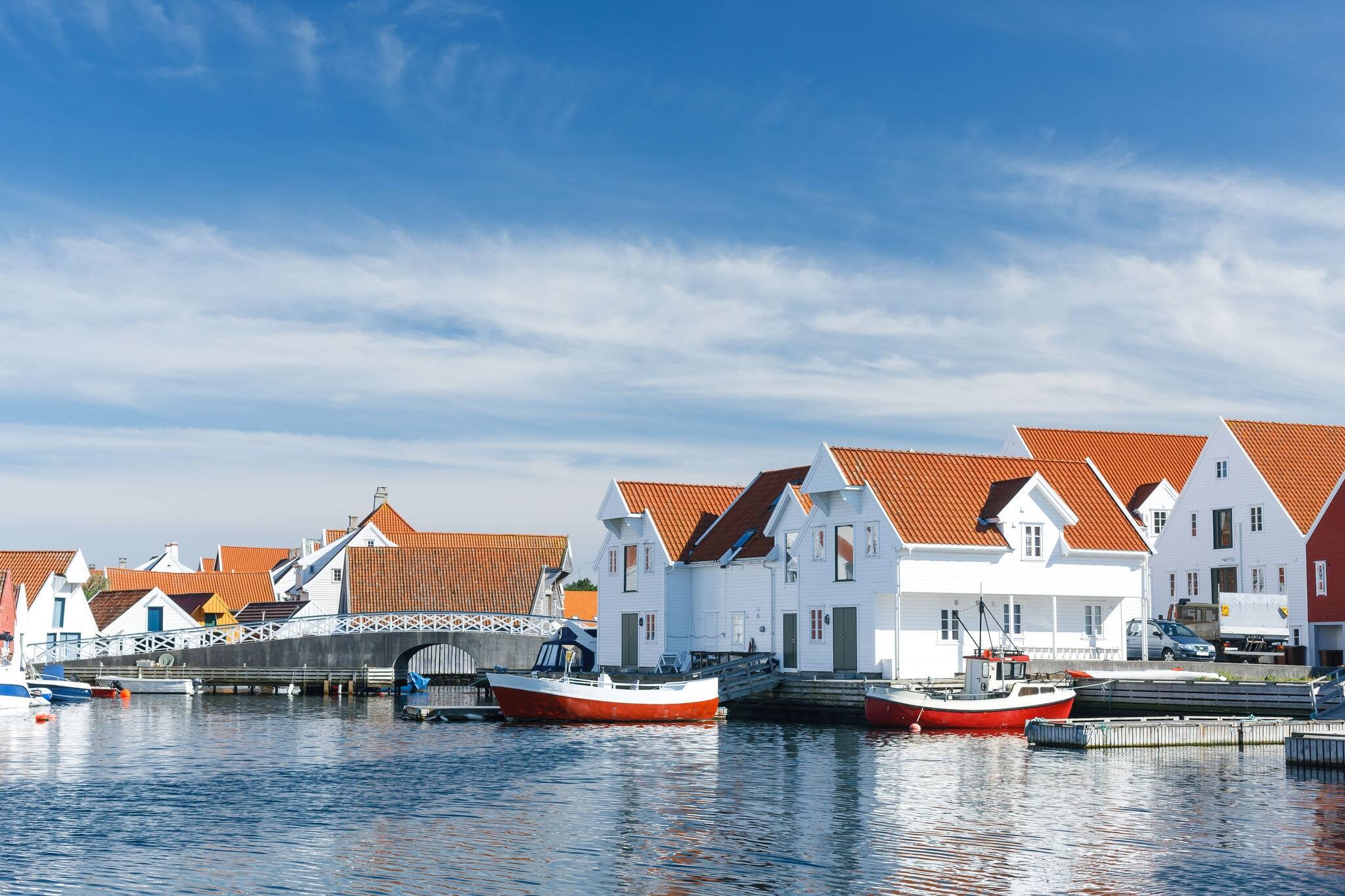 Skudeneshavn village in Norway, white wooden houses with reflections on water
