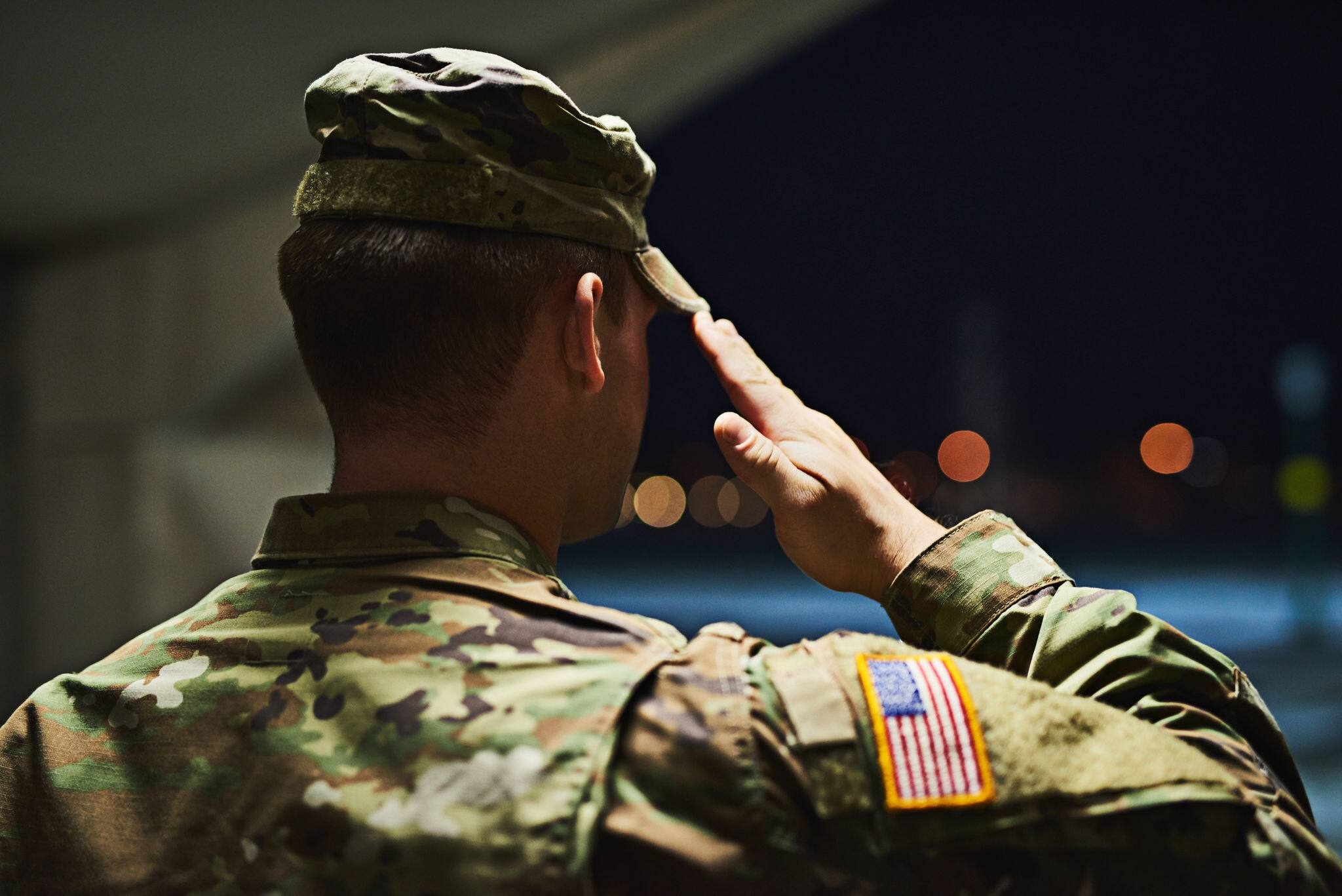 Rearview shot of a young soldier standing at a military academy and saluting