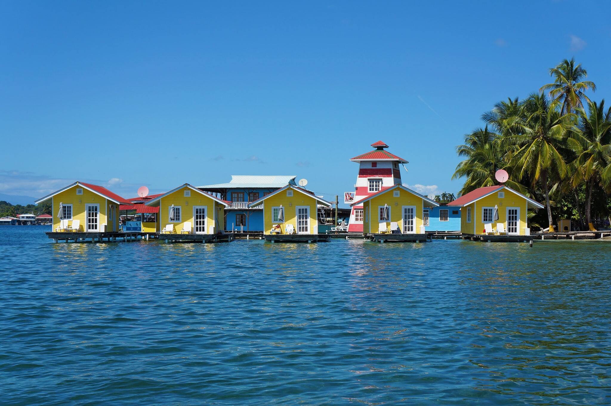 Tropical vacation bungalows over water with coconut trees on the Caribbean sea, Bocas del toro, Carenero island, Panama