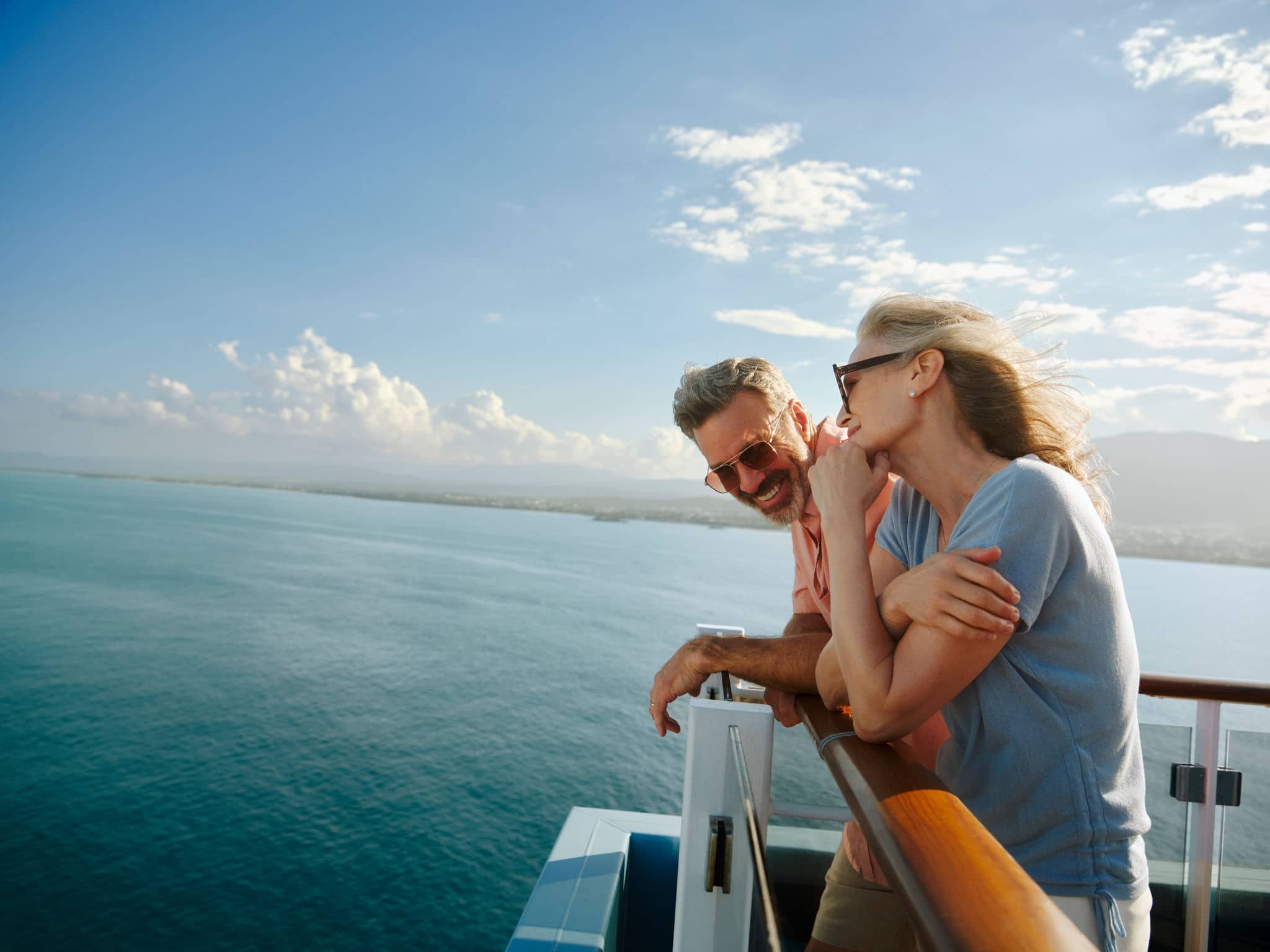 Couple leaning on railing of ship.