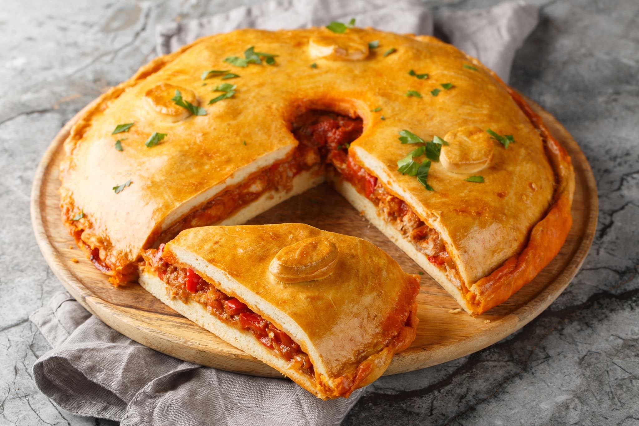 Galician Pie or Empanada Gallega stuffed with tuna or meat and vegetables closeup on the board on the table. Horizontal