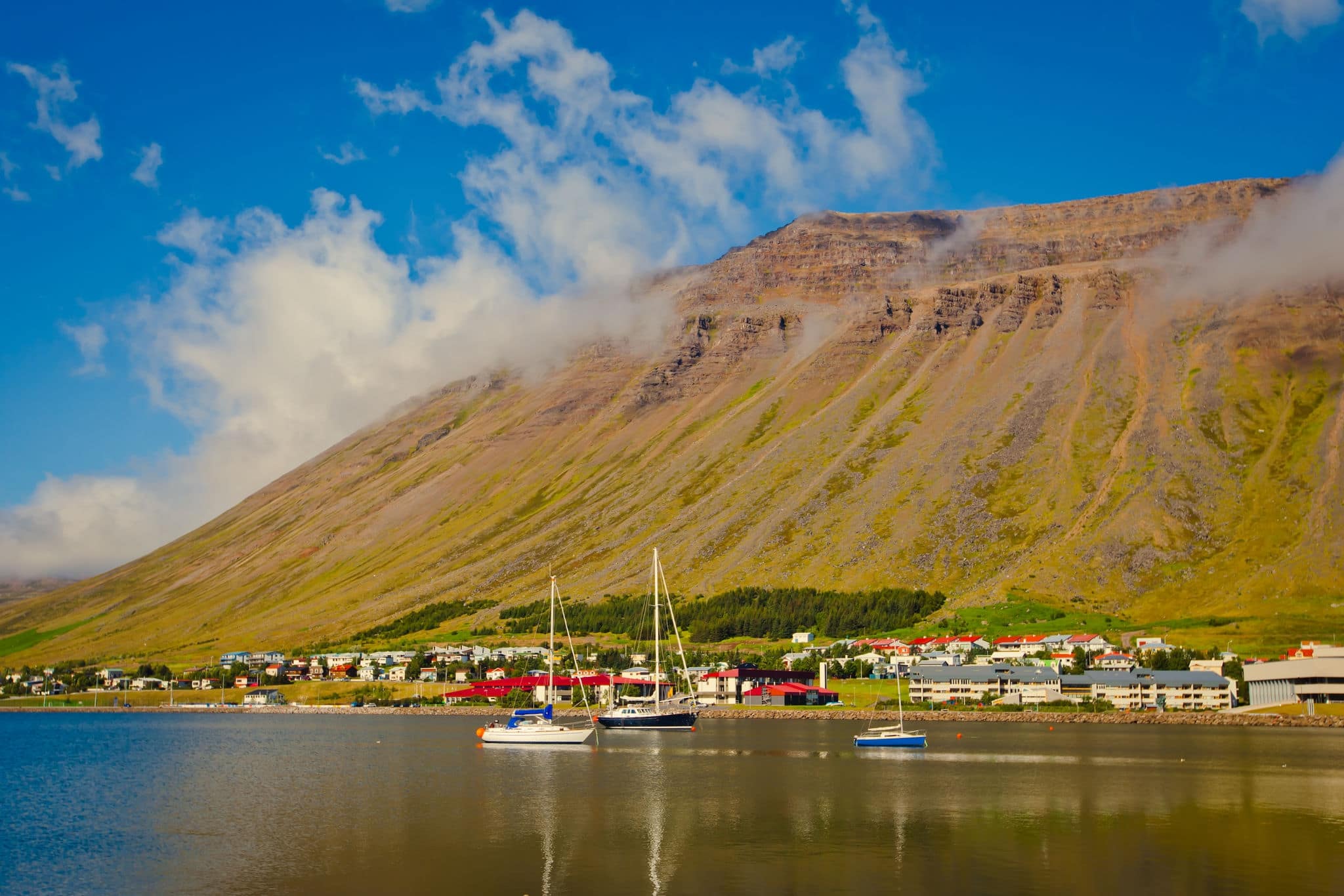 Beautiful view of icelandic fjord and city in iceland with red houses, ships and yachts
