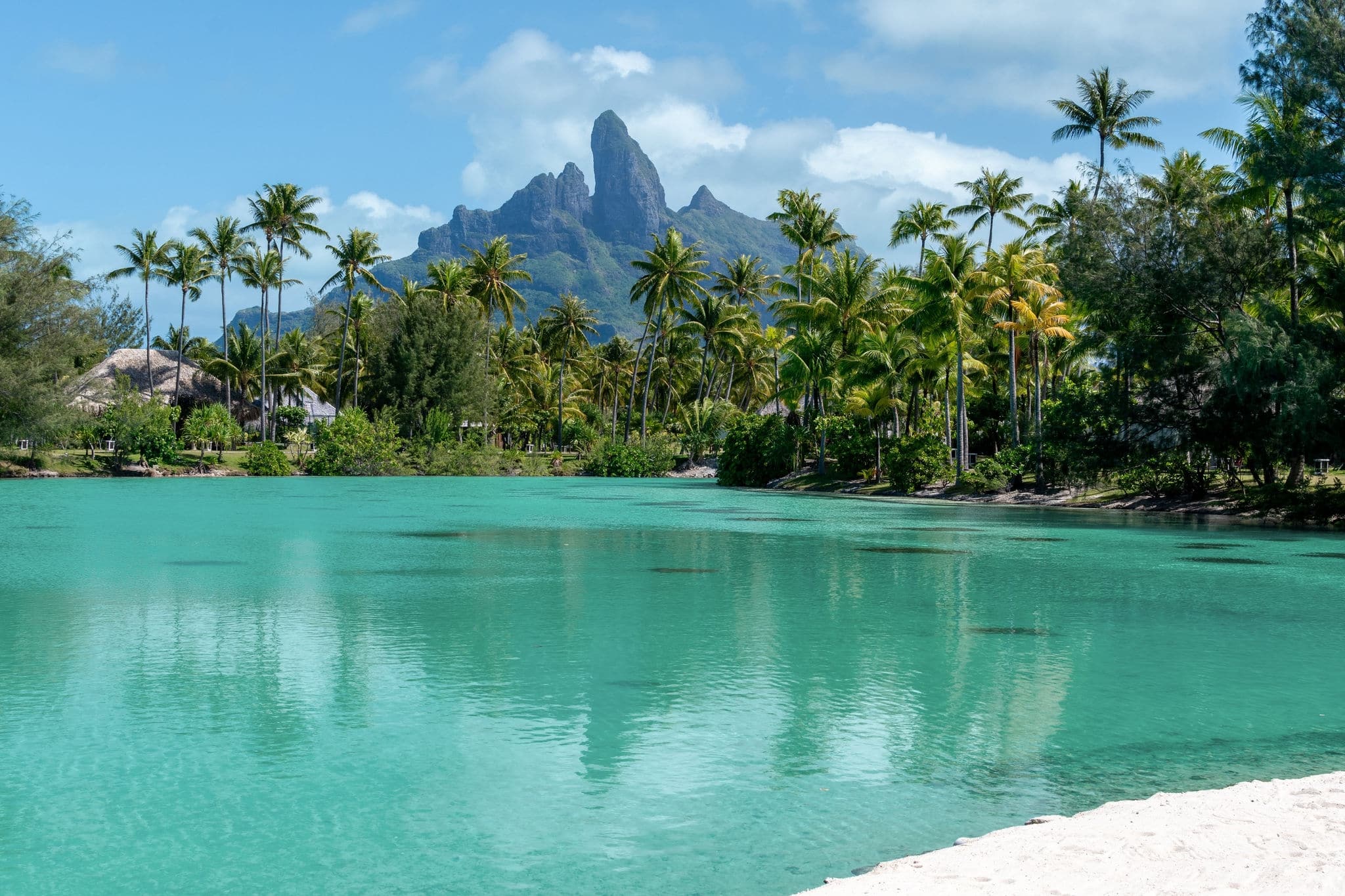 Mt. Otemanu on Bora Bora, Tahiti in French Polynesia as seen from the palm-fringed lagoonarium at the St. Regis Resort. White sand beach fronts the spa behind, where couples massages are a specialty.