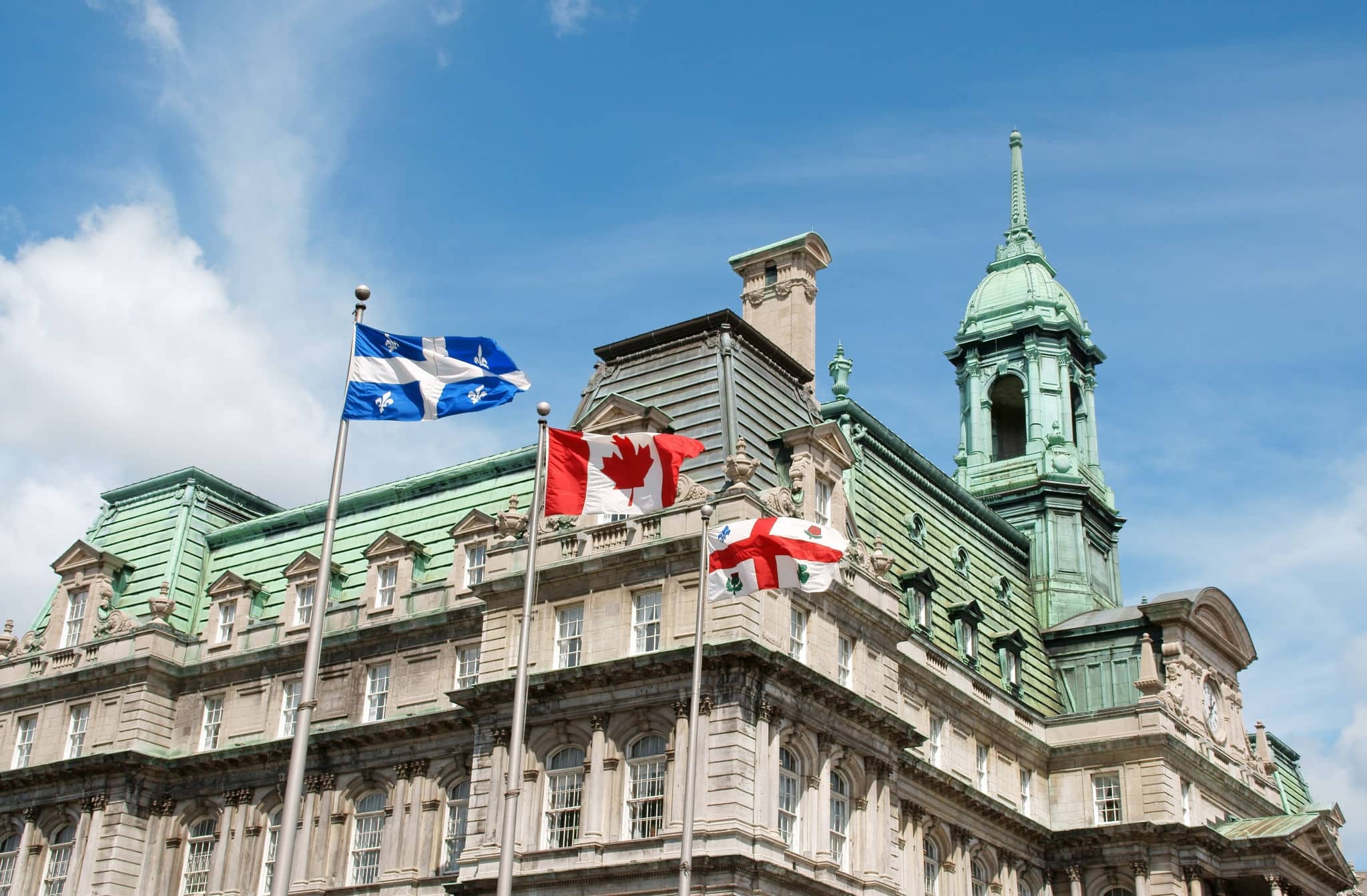 Old Montreal City Hall and flags of Quebec, Canada and the city