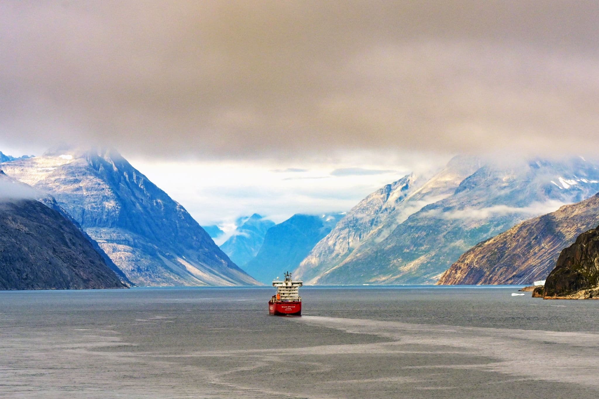 Scenic landscape view of the cargo supply ship Malik Arctica sailing up the Prince Christan Sound fjord in Greenland. 