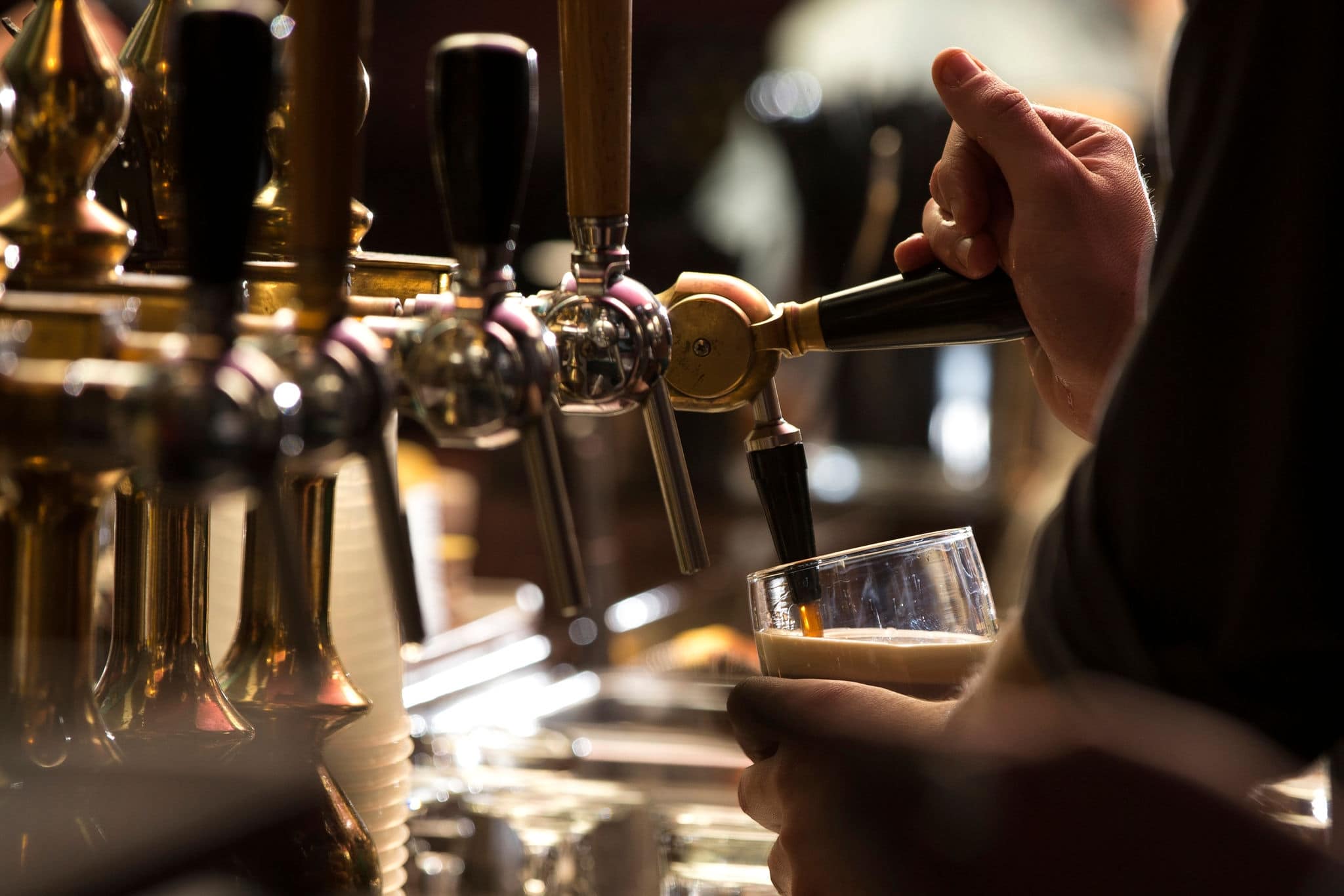 closeup of a bartender pouring a dark stout beer in tap with subject and focus on the right
