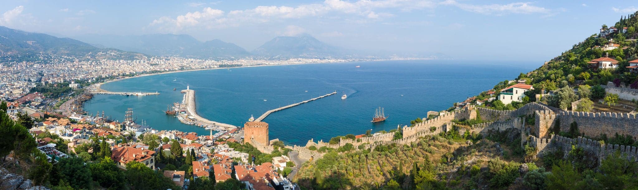 Panoramic view of sea port of Alanya. In the foreground the ruins of an ancient fortress. In the background of the Taurus mountains and residential neighborhoods of Alanya. Turkey.