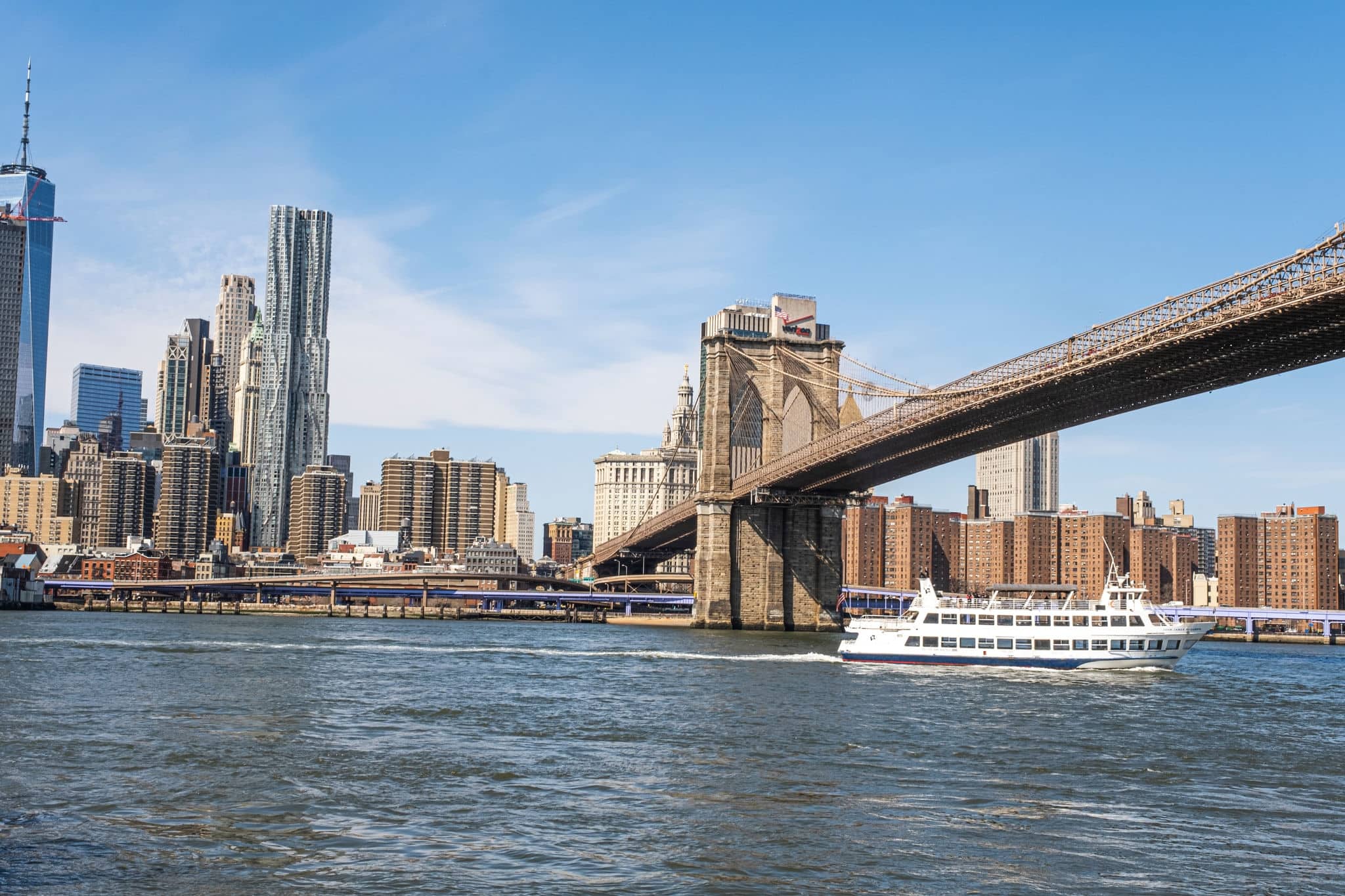 A ferry passing under the Brooklyn Bridge