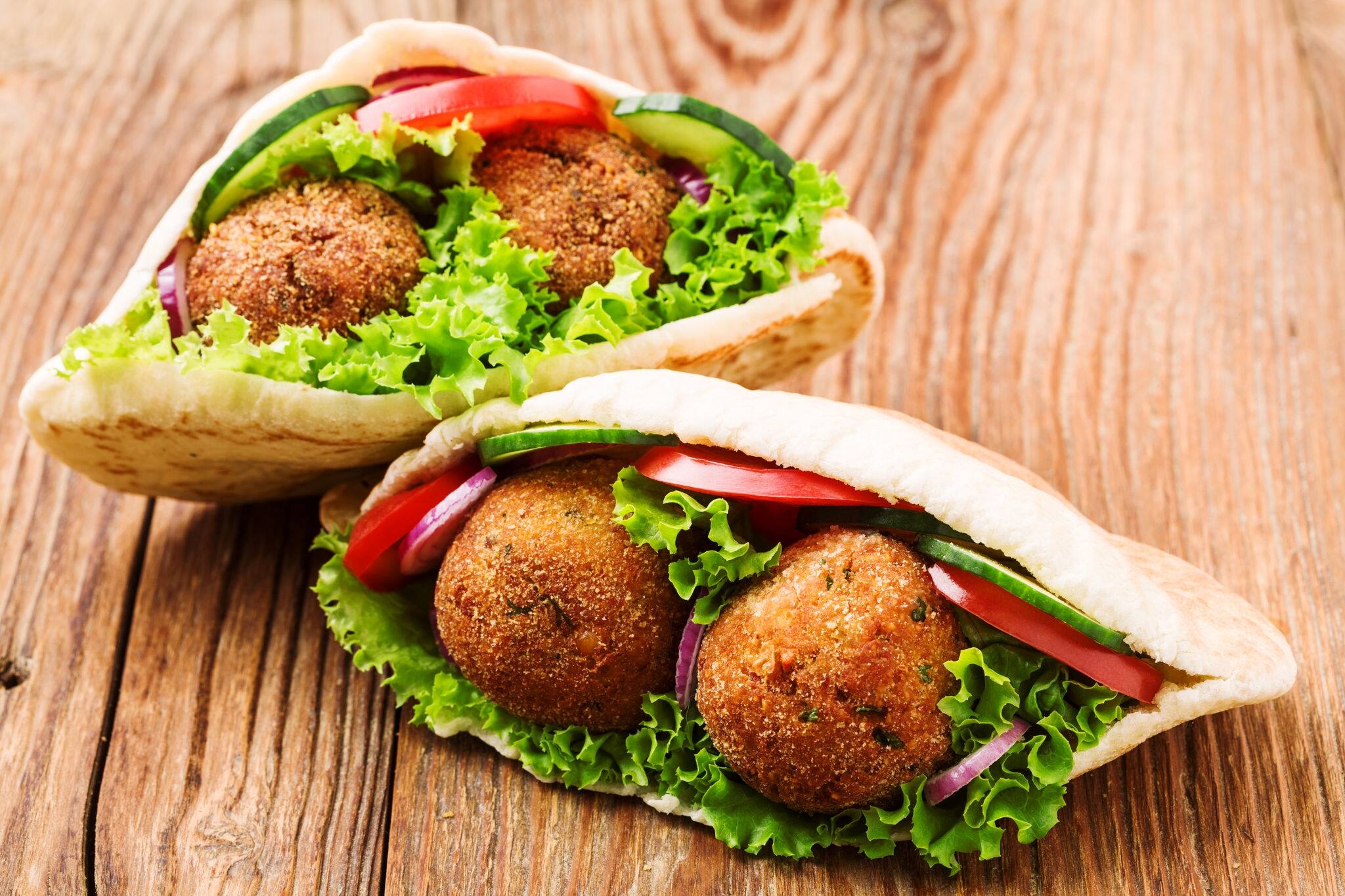 Falafel and fresh vegetables in pita bread on wooden table