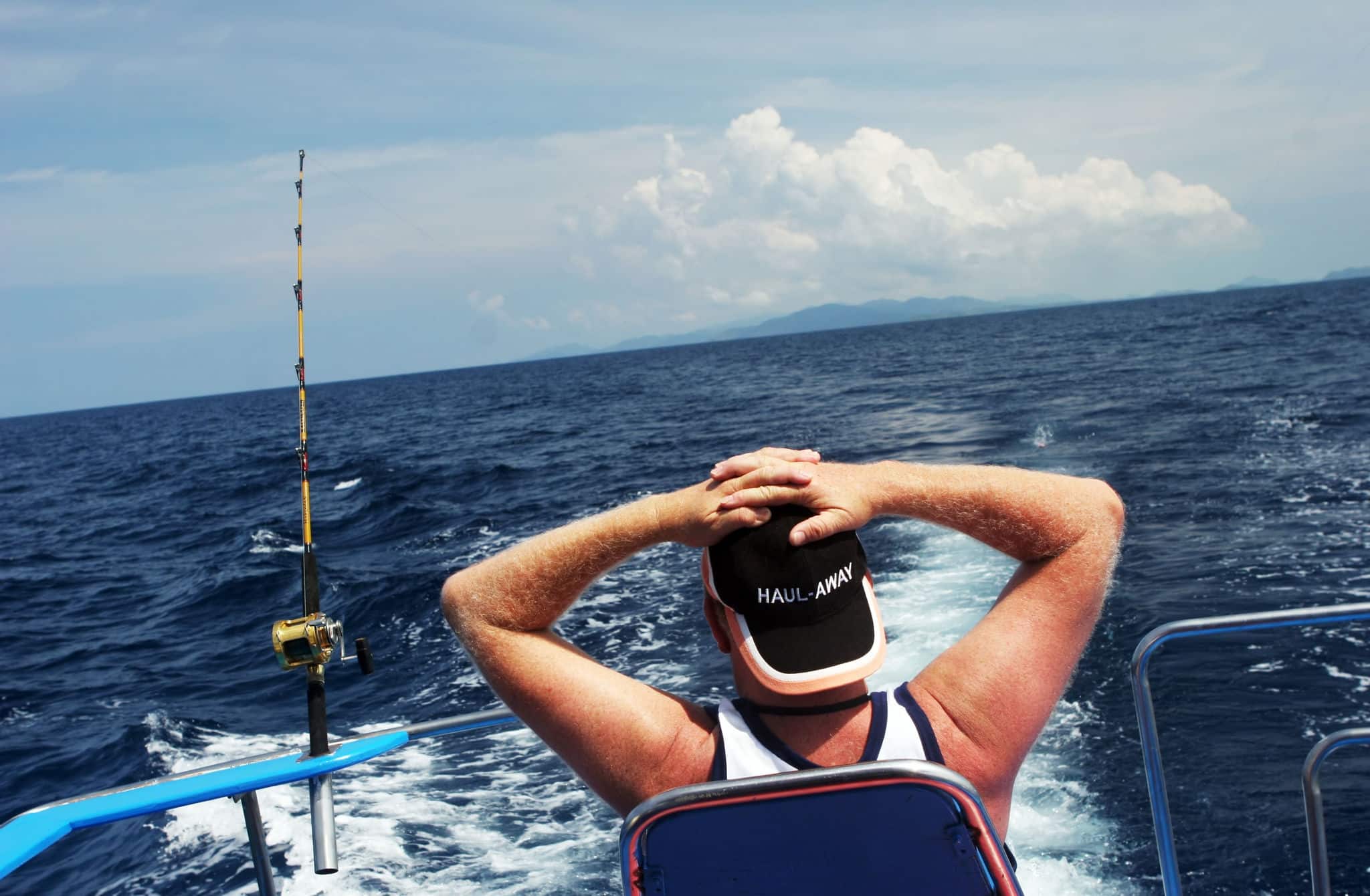 Man on a boat deep sea fishing is relaxing and waiting for the fish to come.