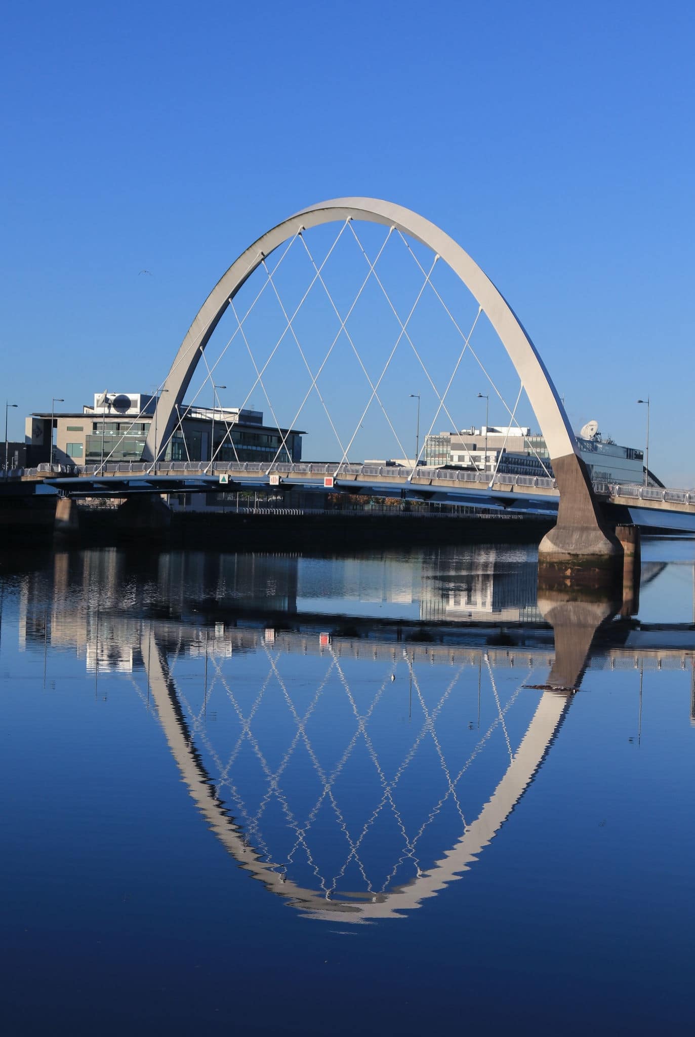 Clyde Arc Bridge at sunrise  on River Clyde in Glasgow, Scotland.  Beautiful reflection of buildings in water.
