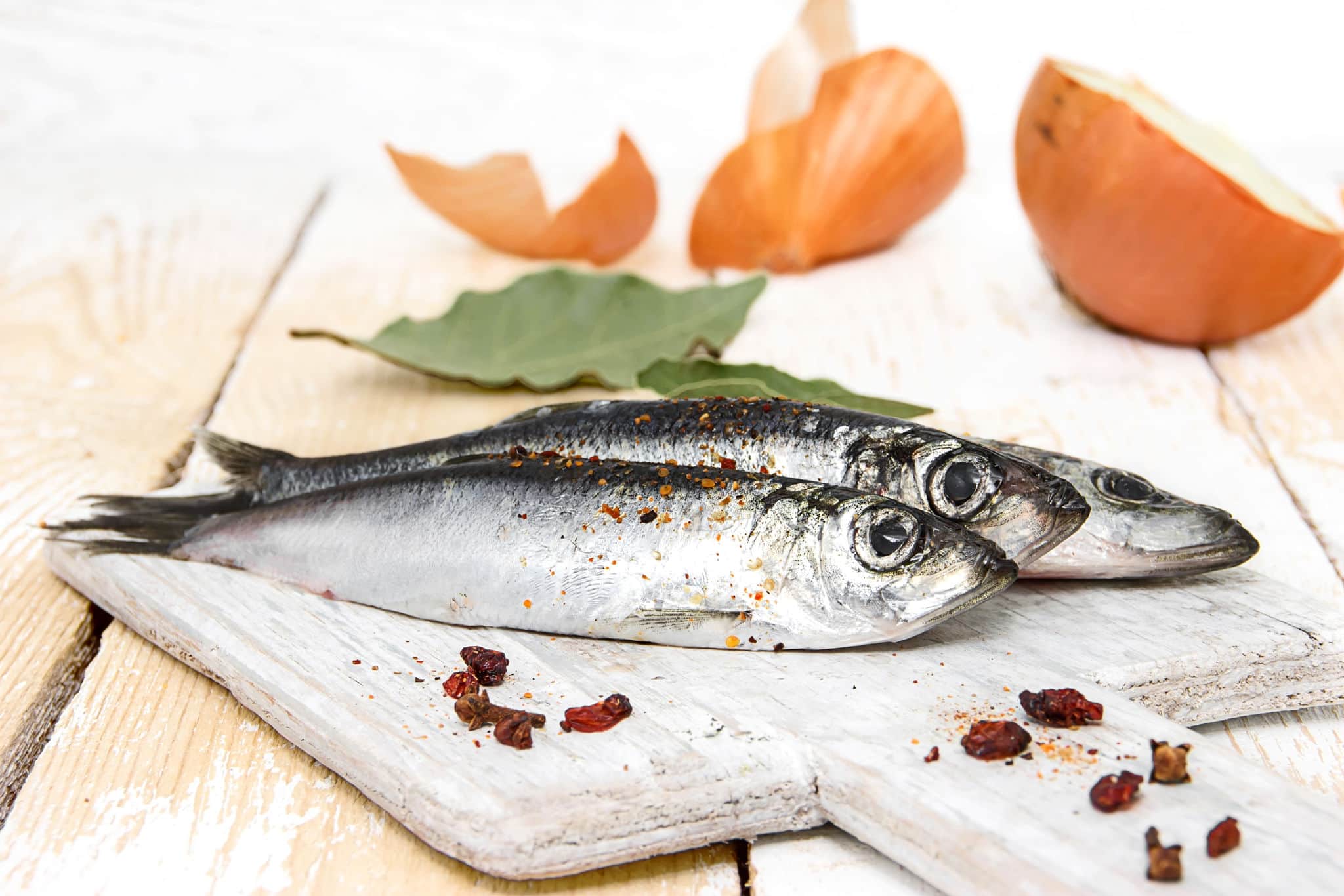 Freshly caught herring with spices on the wooden background