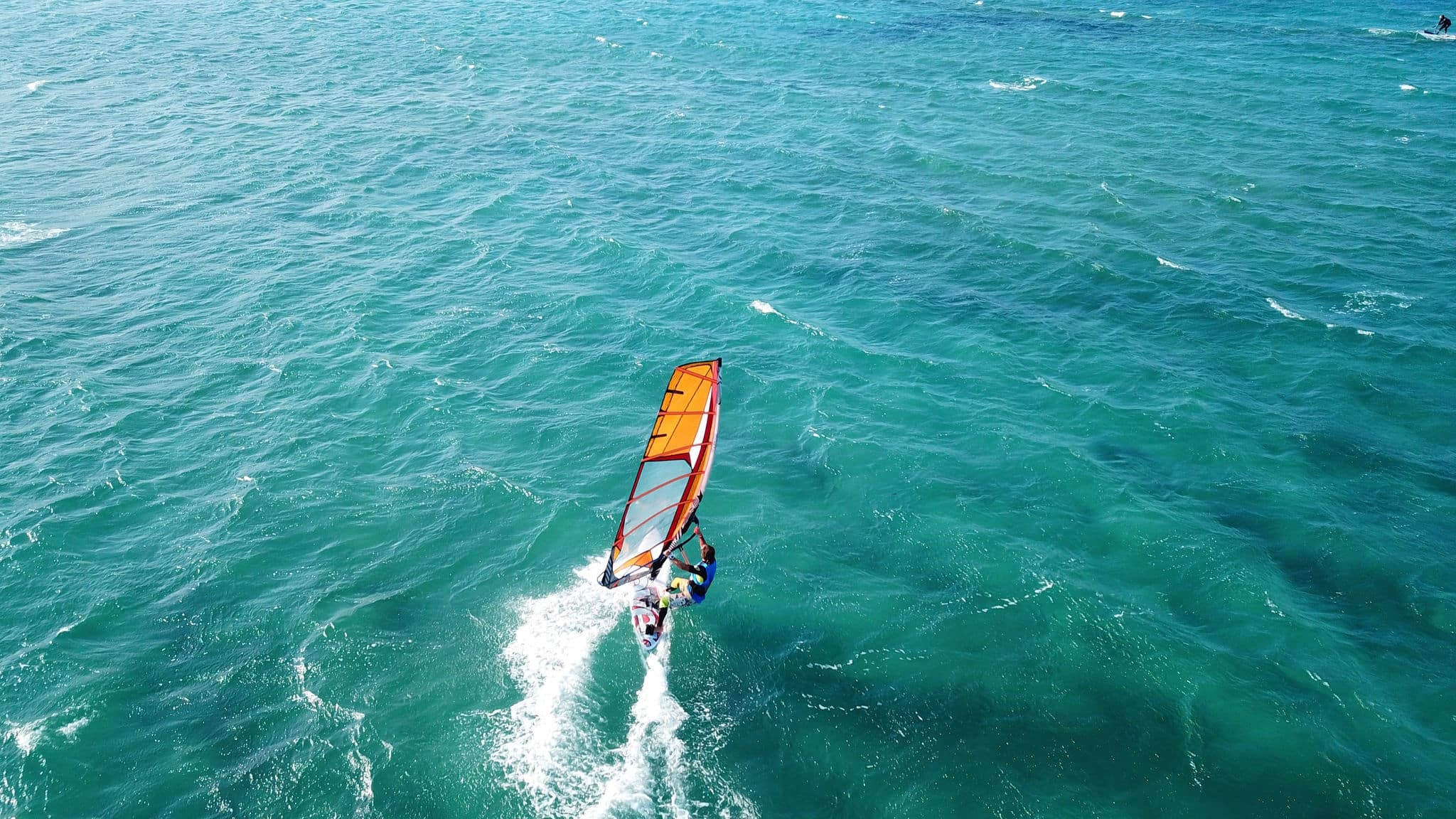 Aerial drone photo of surfer cruising in high speed in popular wavy beach of Chrysi Akti, Paros island, Cyclades, Greece