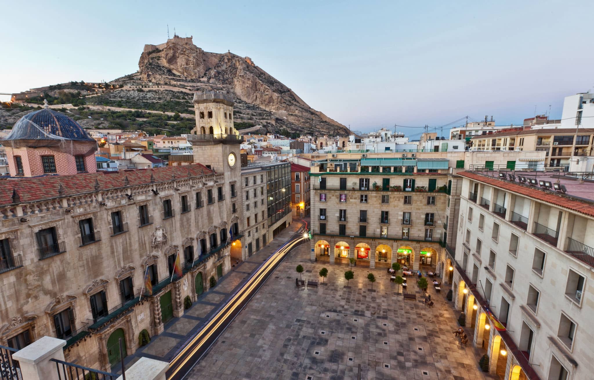 Beautiful architecture around an urban square in Alicante, Spain with an early morning view across to the castle of Santa Barbara