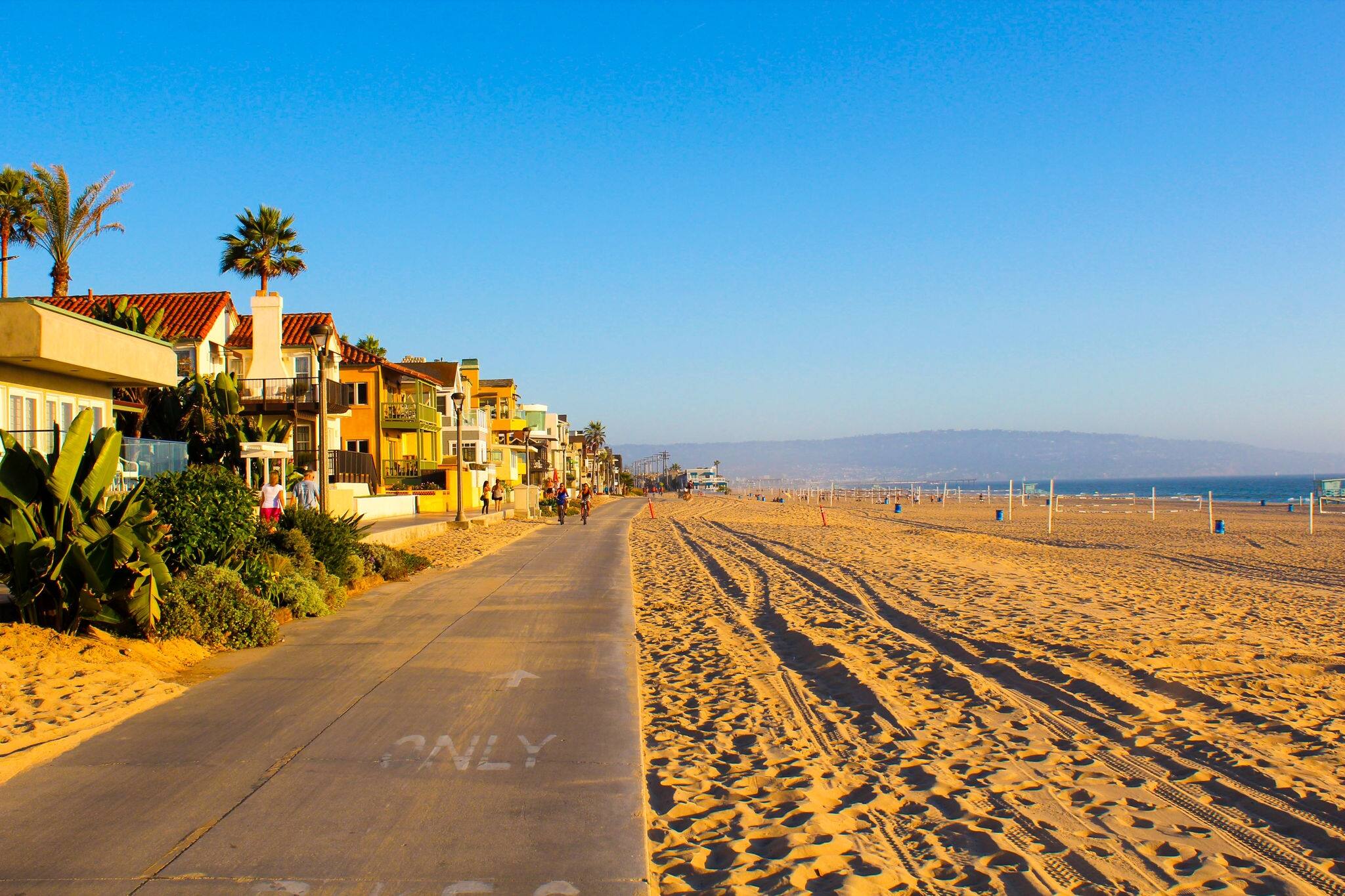 Beautiful Venice beach area in Los Angeles with a pedestrian walk during orange sunset. Empty beach, golden sand, no people.