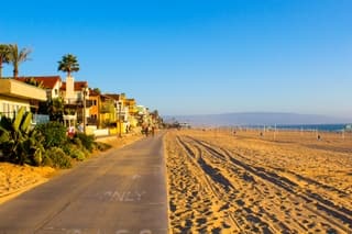 Beautiful Venice beach area in Los Angeles with a pedestrian walk during orange sunset. Empty beach, golden sand, no people.