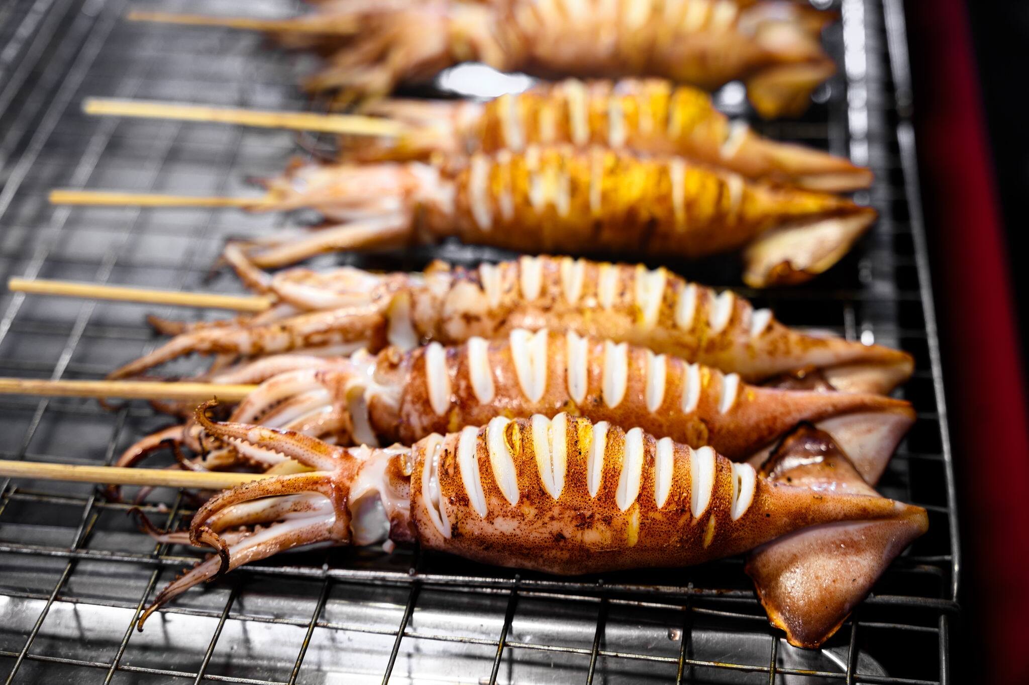 Grilled squid skewers on a charcoal stove in street food market