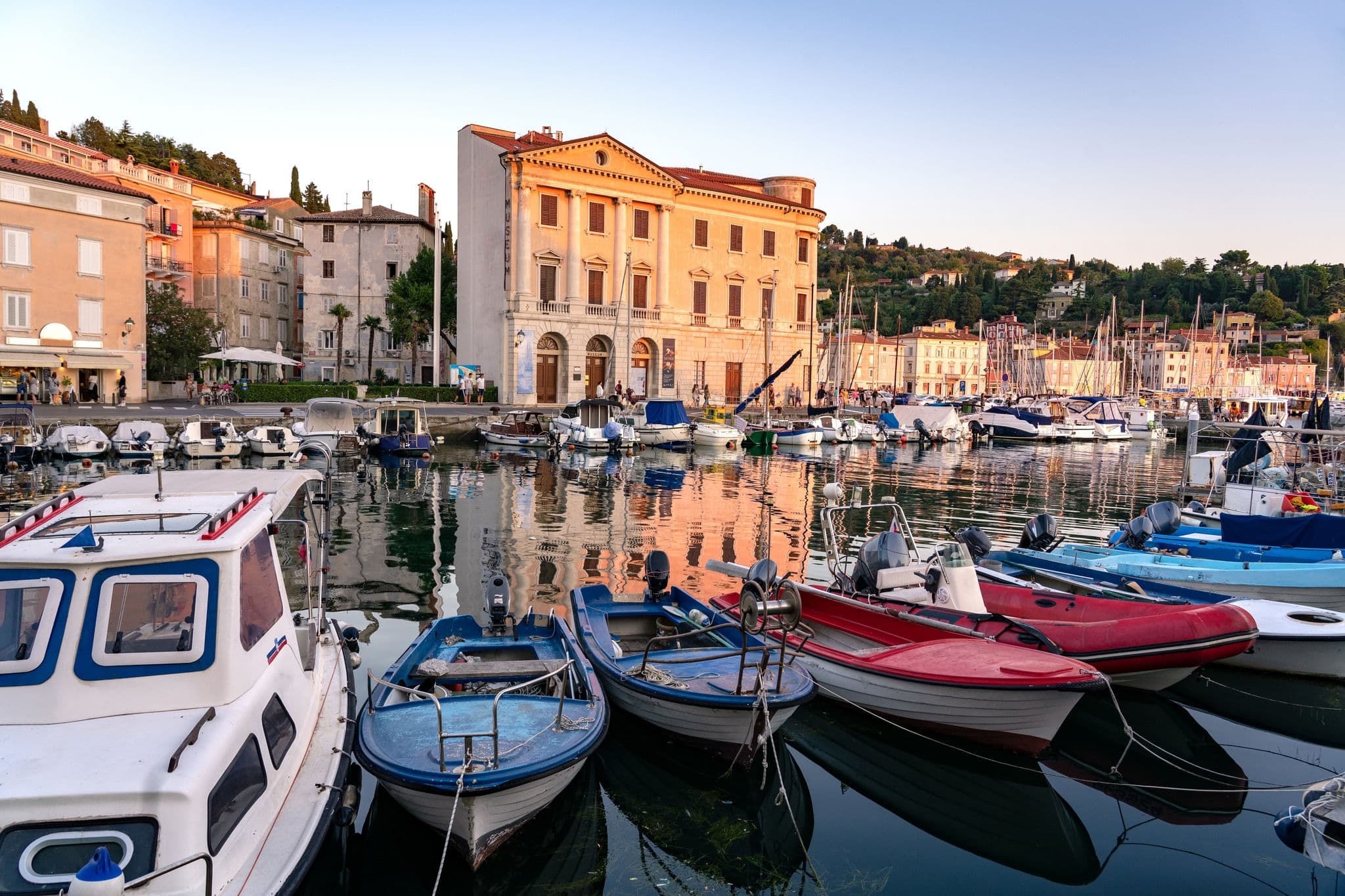 Piran harbour with boats in the sunset .