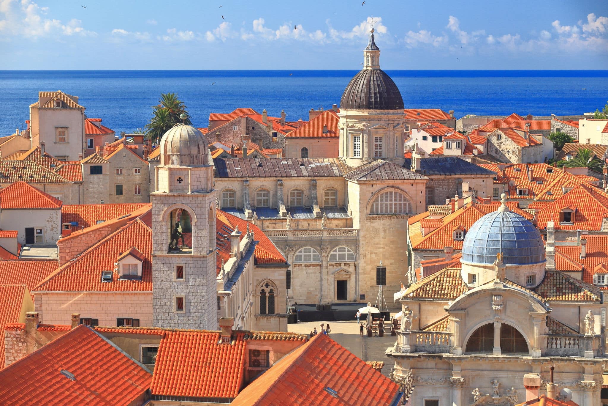 Tall church domes and the medieval clock tower above roof tops inside Dubrovnik old town, Croatia