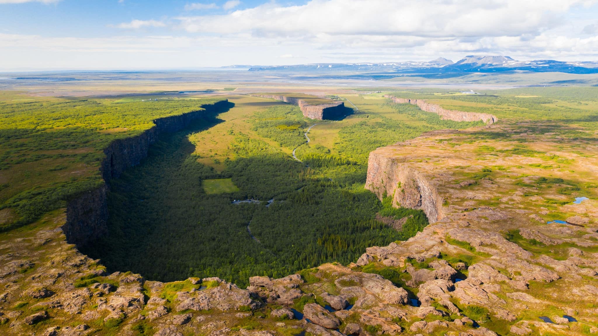 Aerial view of Asbyrgi canyon in a sunny day and cloudy blue sky on the background