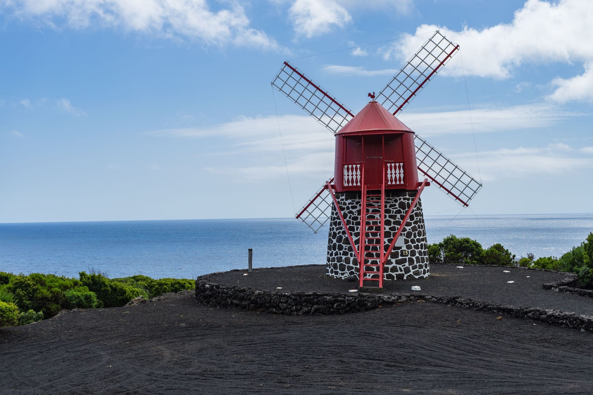 Seascape with scenic red windmill on the coast of Pico Island, Azores, Portugal