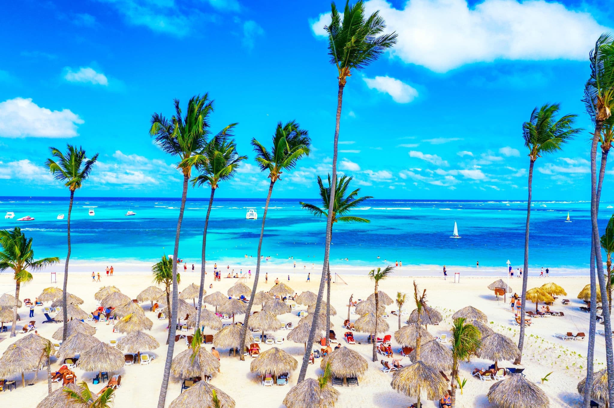 Aerial drone view of beautiful caribbean tropical beach with straw umbrellas, palms and boats. Bavaro, Punta Cana, Dominican Republic. Vacation background