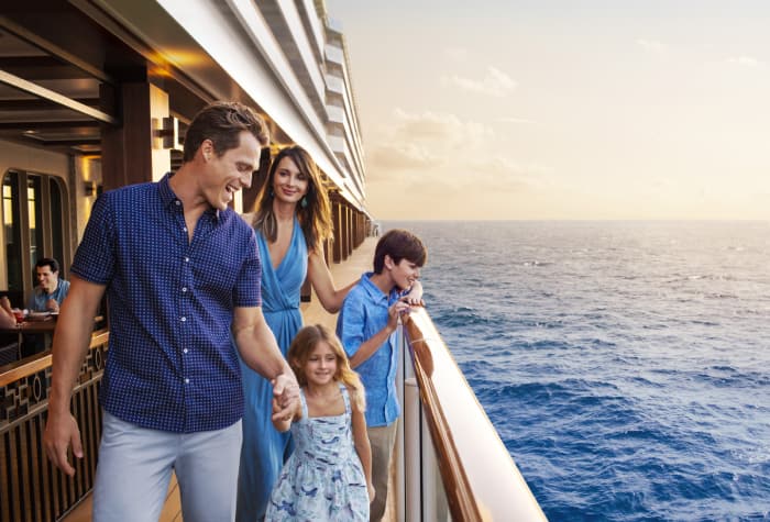 Una familia de 4 paseando por la pasarela del crucero Norwegian Escape contemplando el mar sereno