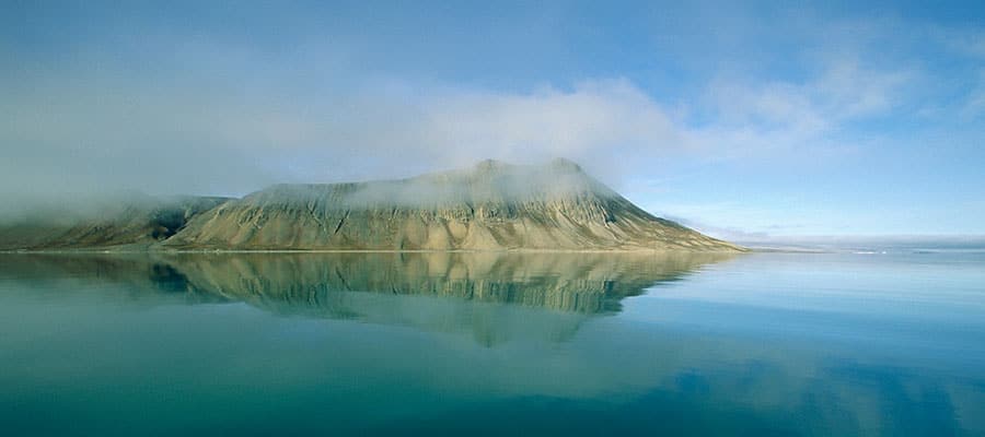 Take in the serene Isfjorden reflecting off the peaceful Arctic waters