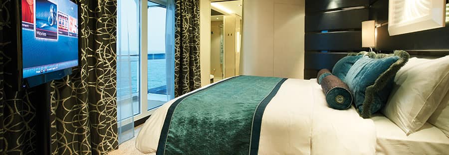 Schlafzimmer der Deluxe Owner's Suite mit großem Balkon auf der Norwegian Getaway