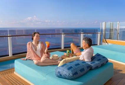 A couple relaxing onboard Norwegian Prima cruise ship at the infinity beach on lounger
