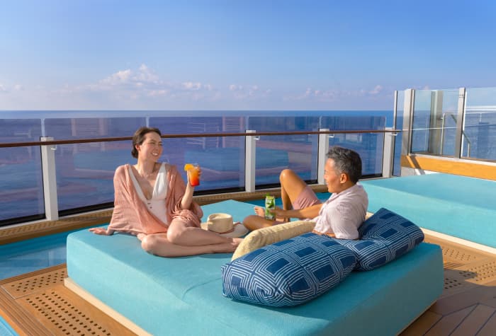 Una pareja relajándose en una reposera en la "infinity beach" a bordo del crucero Norwegian Prima