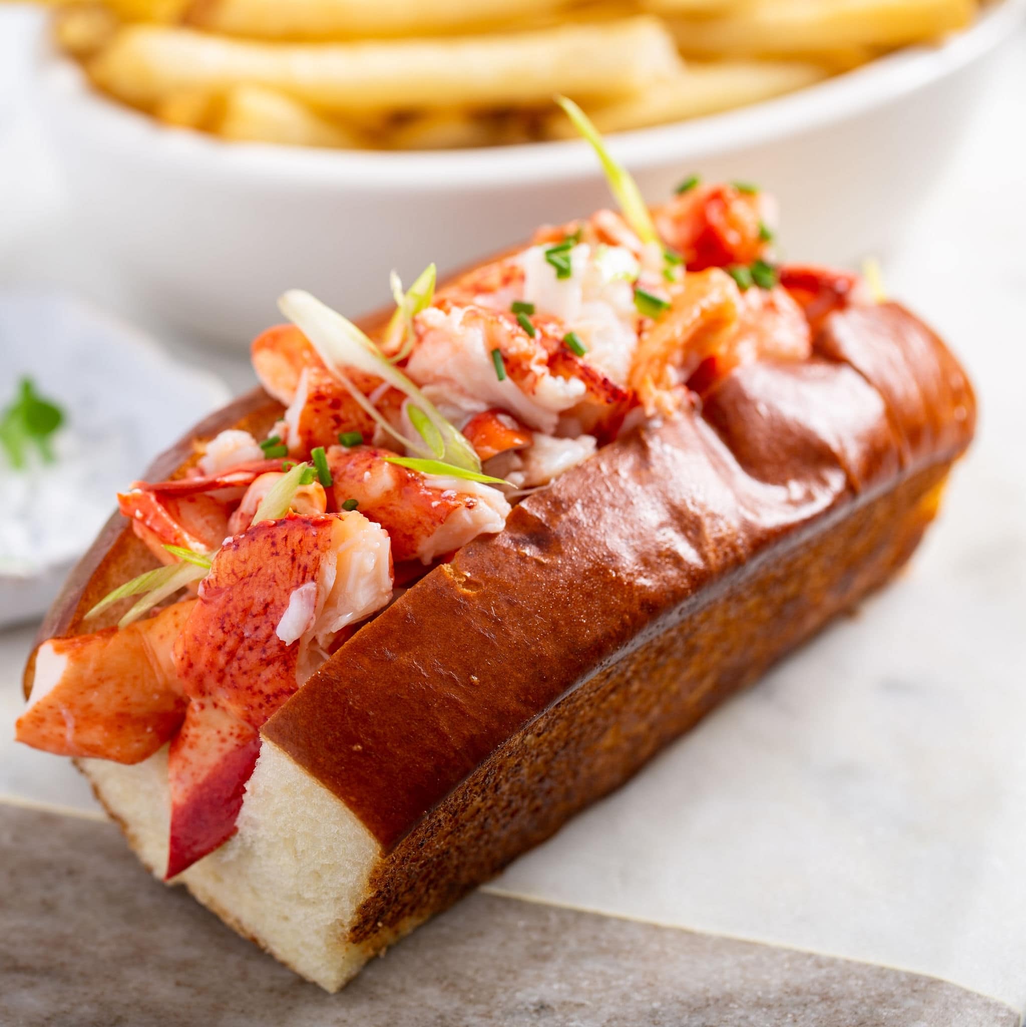 NCL-RhodeIsland-Newport-Cruise-Foodie-Lobster-Rolls .jpg Lobster roll on a brioche bun with fries on a marble board